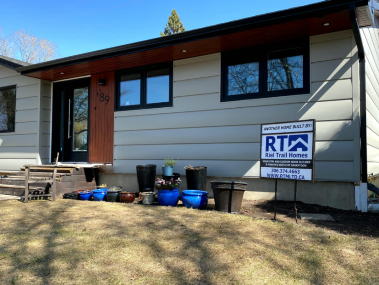 Street view — horizontal metal siding with warm woodgrain accent panels and black trim in Saskatoon.