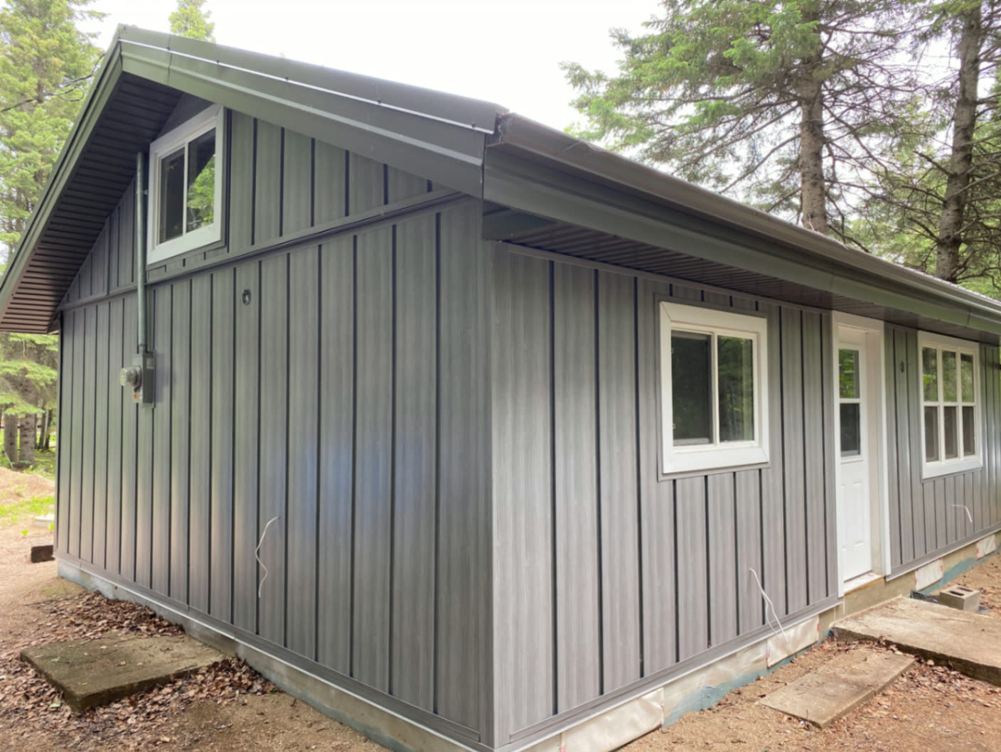 Front corner — vertical woodgrain-look metal siding with matching soffit, fascia, and eavestrough.