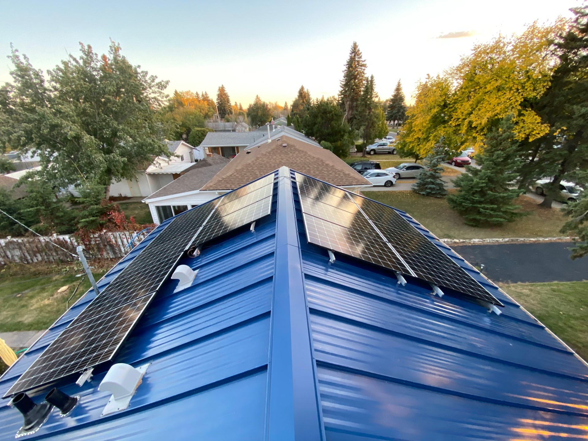 Solar panels clamped to both slopes of a blue standing seam metal roof with no roof penetrations