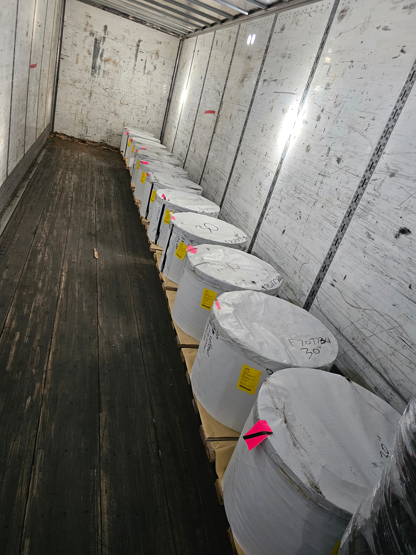 A row of wrapped and palletized pre-finished steel coils staged inside a delivery trailer for Sask Seamless