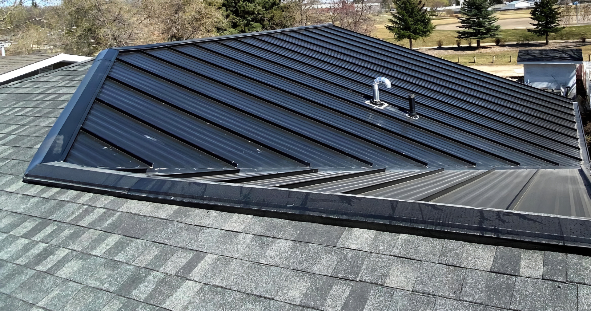 Standing seam metal roof on the solar slope with asphalt shingles on the adjoining slopes of a Saskatchewan home