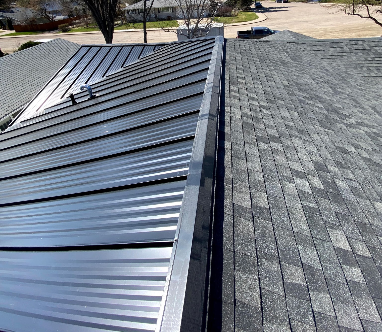 Close view of the colour matched transition flashing where standing seam panels meet asphalt shingles