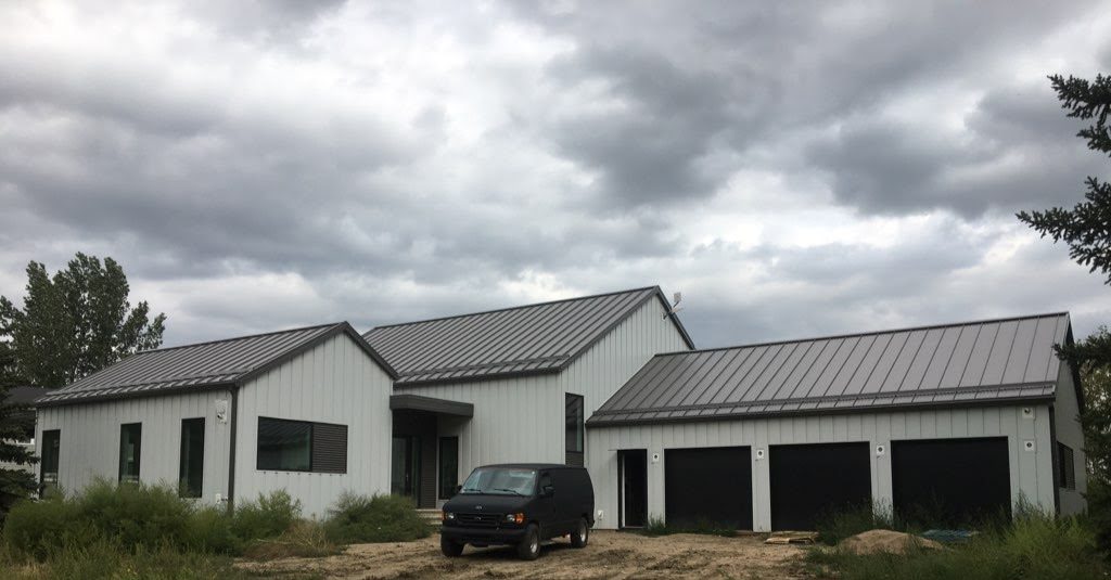 Front elevation — charcoal standing seam metal roof over light grey board-and-batten steel siding, RM of Saskatoon.