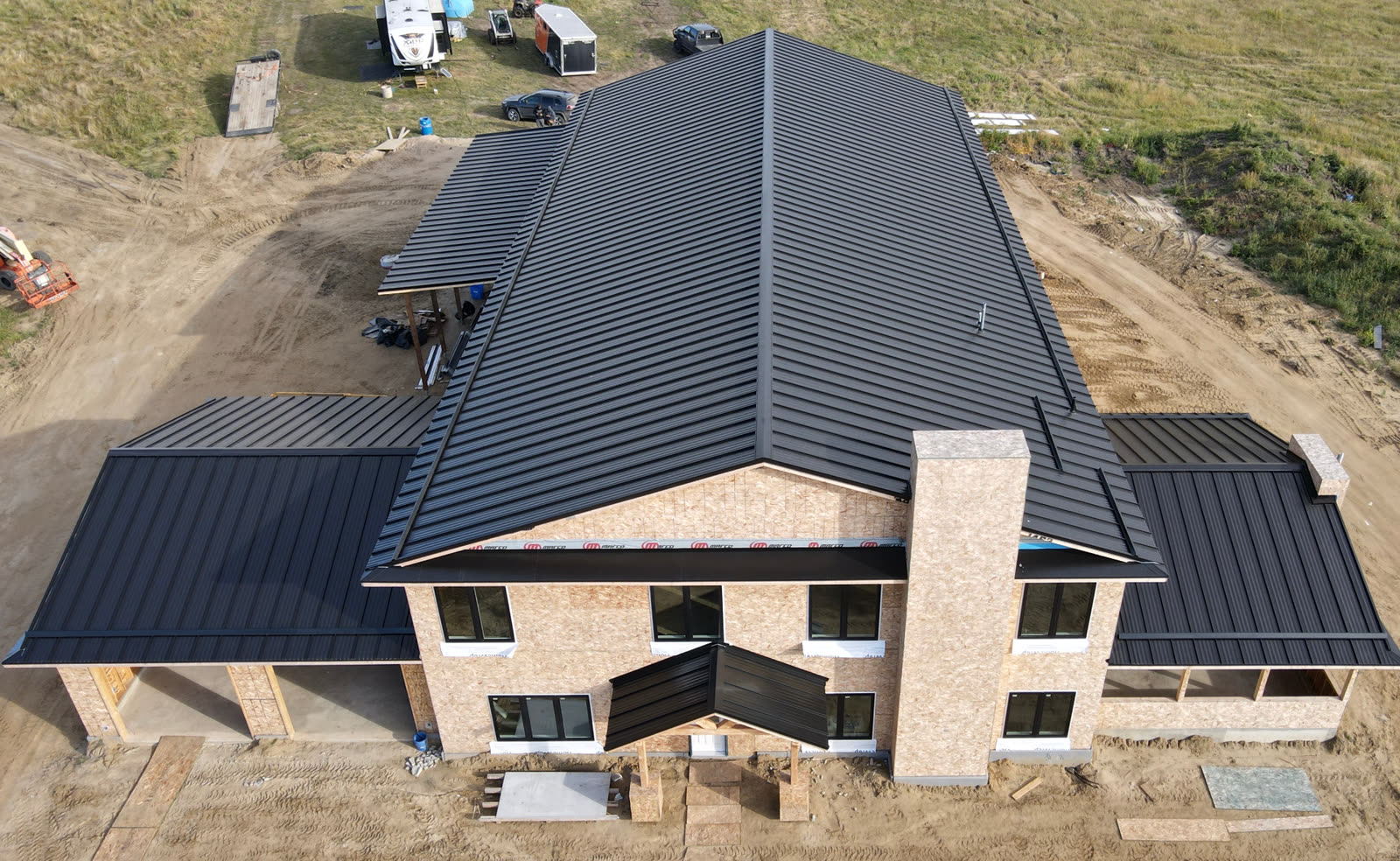 Aerial view — black standing seam metal roof on a large Prince Albert acreage home.
