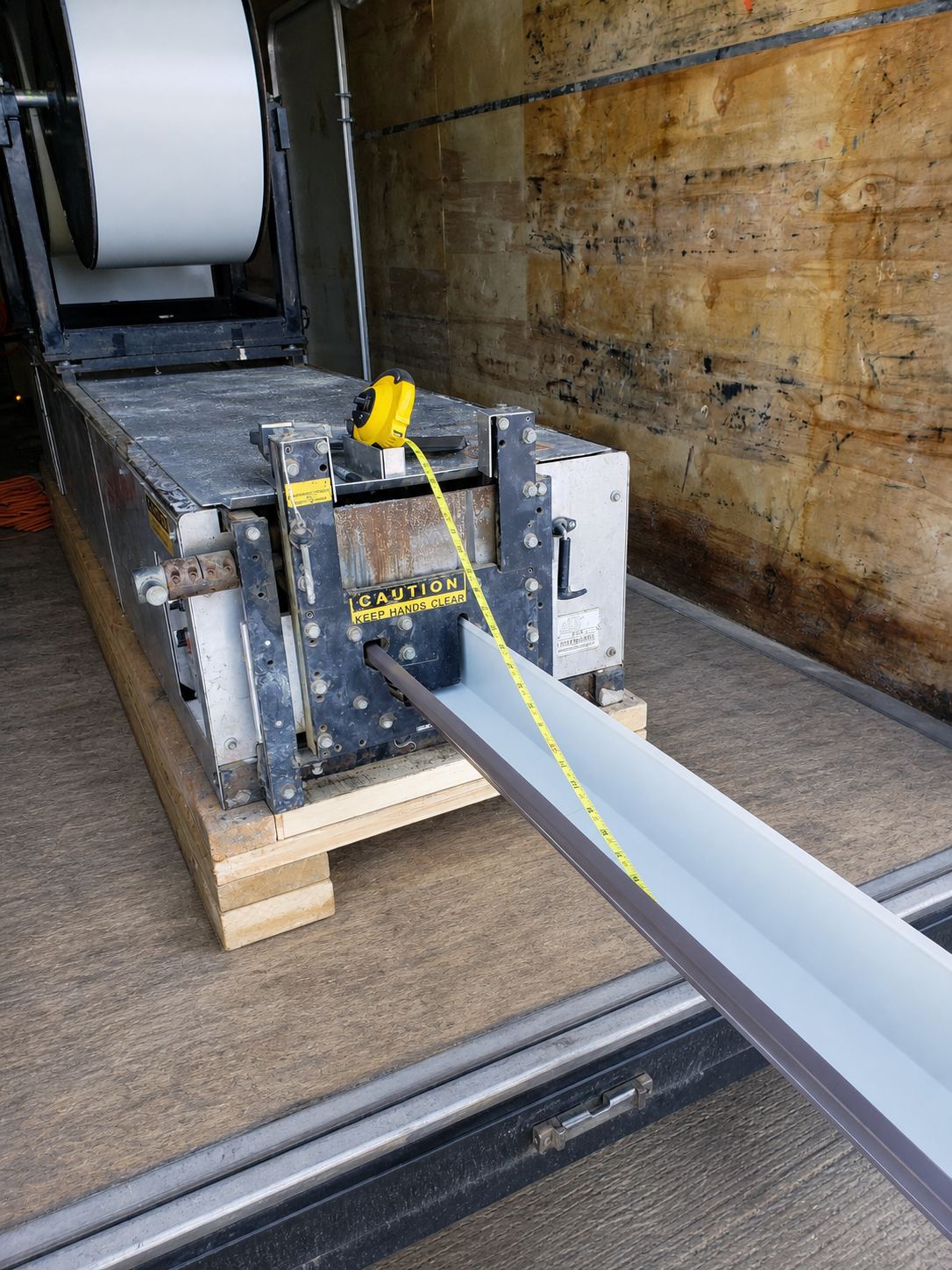 Inside our trailer — roll-former producing a fresh seamless eavestrough length, measured on the spot